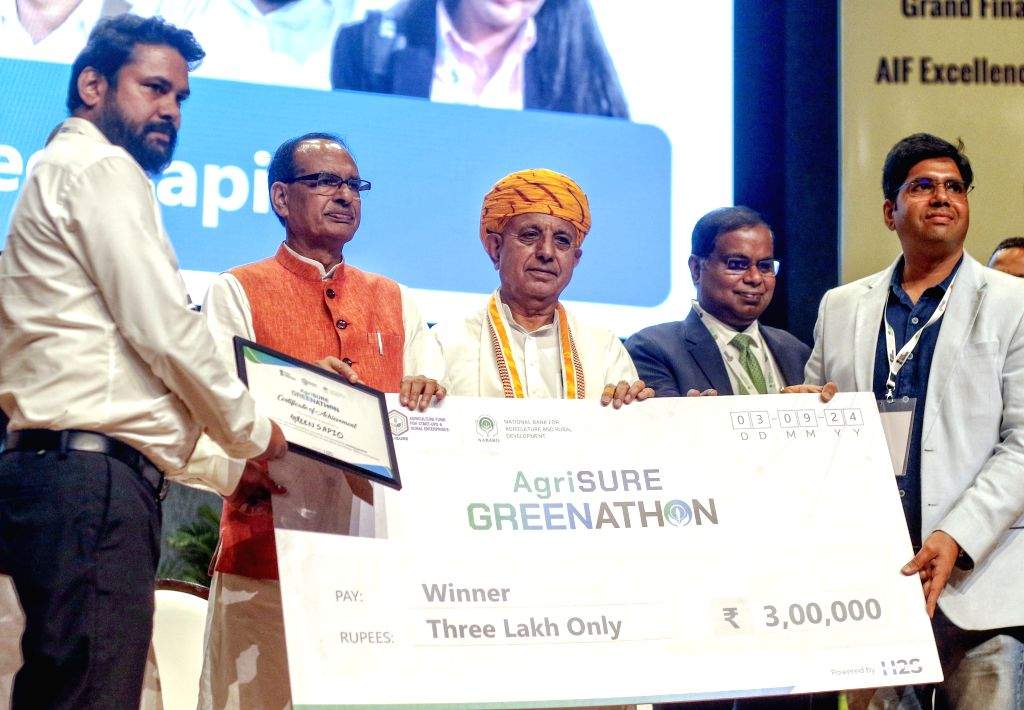 Bhagirath Choudhary and Union Minister Shivraj Singh Chouhan hand an oversized AgriSURE Greenathon cheque for three lakh rupees to a winning team on stage
