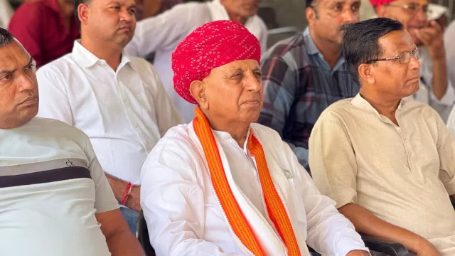 Bhagirath Choudhary seated among men at a public meeting