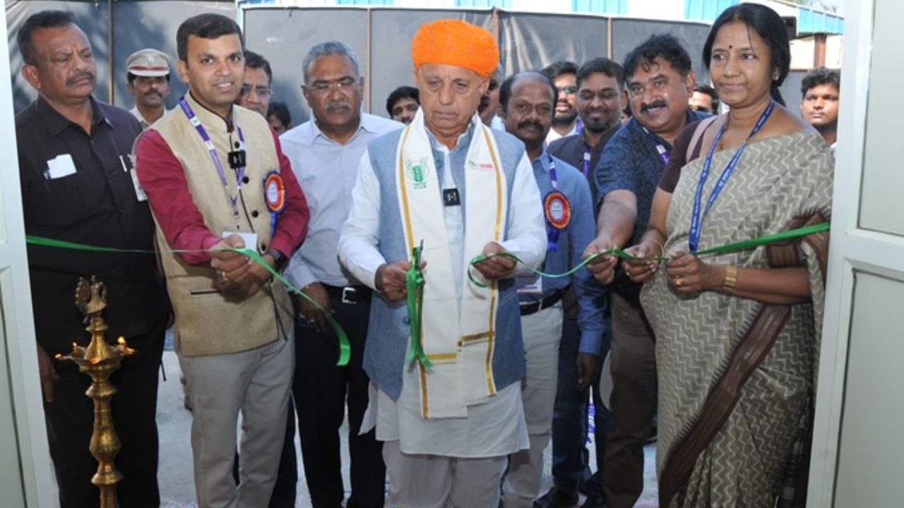 Bhagirath Choudhary, in an orange turban and an ICAR stole, cuts a green ribbon with officials at the entrance to an exhibition, beside a brass lamp