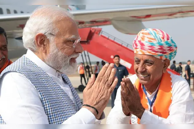 Bhagirath Choudhary, in a multicoloured turban, greets Prime Minister Narendra Modi with folded hands on an airport apron