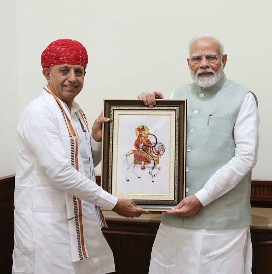 Bhagirath Choudhary, in a red turban, presents a framed miniature painting of a horseman to Prime Minister Narendra Modi