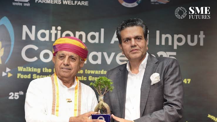 Bhagirath Choudhary receives a potted bonsai memento from a host on stage at the National Agri Input Conclave